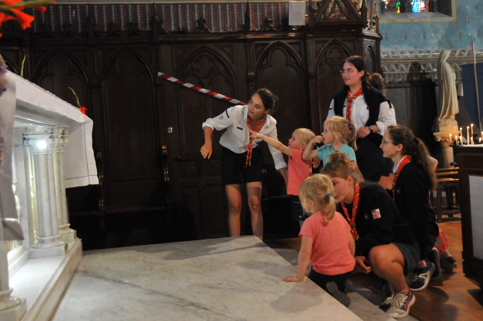 des jeunes filles scouts présentent l'autel d'église à des enfants