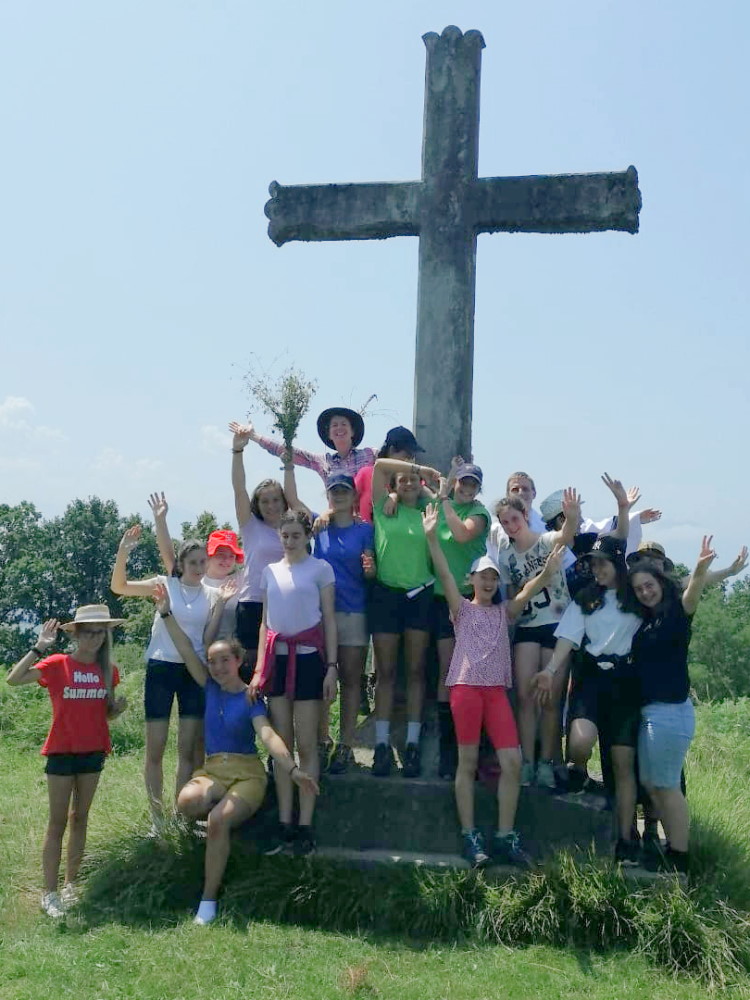 groupe de jeunes filles joyeuses au pied d'une croix à la campagne