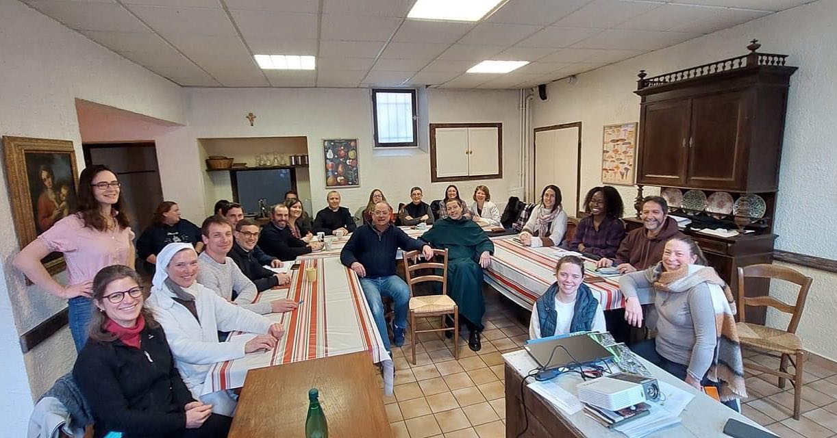 groupe de personnes assises souriantes dans une salle prêtes pour recevoir un enseignement